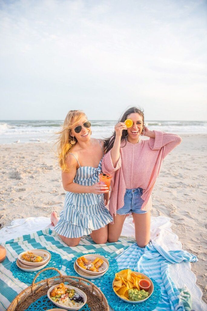 Meet the team at Agave Azul sitting on a beach blanket on Topsail Beach, NC