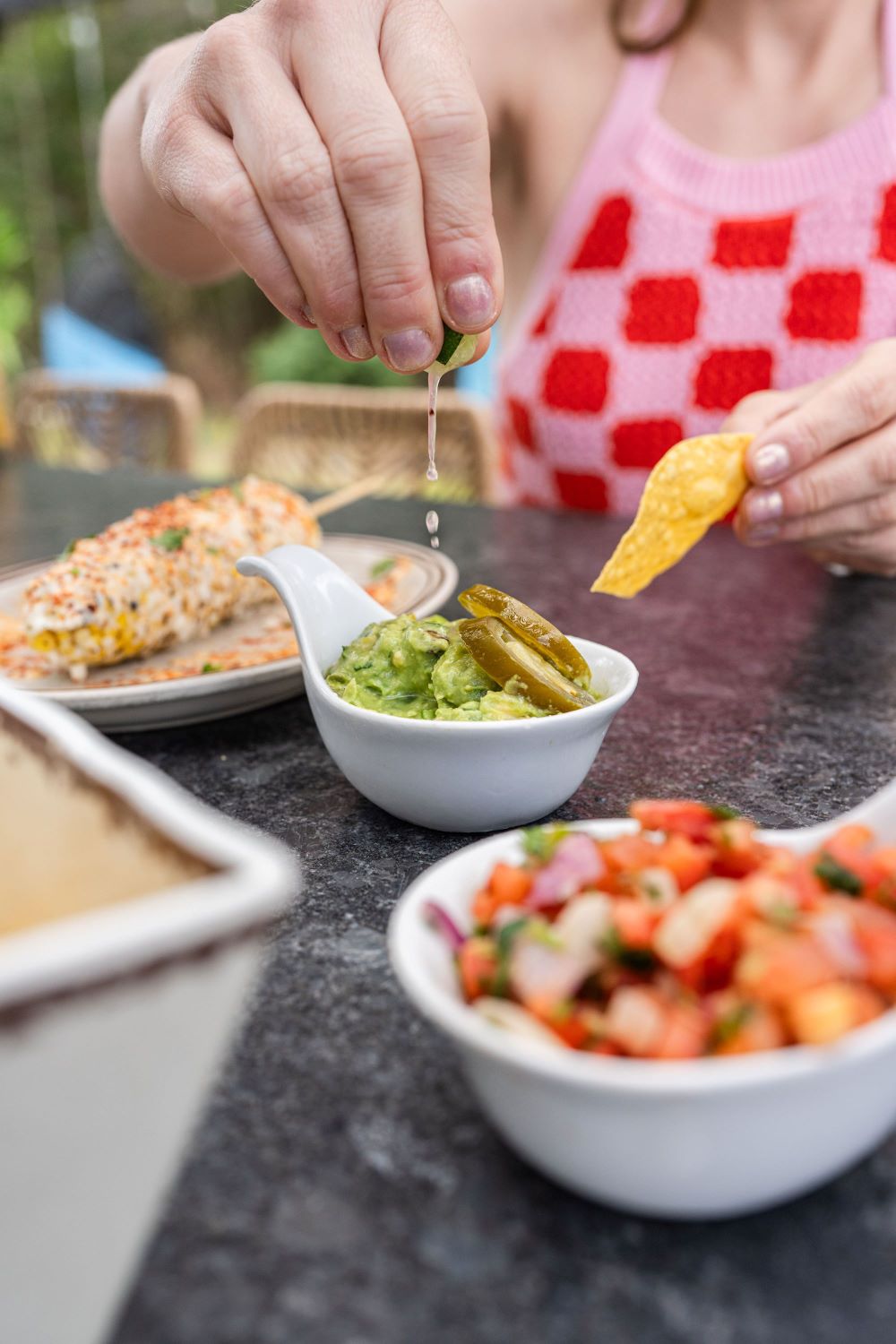 lime squeezed into an appetizing bowl of guacamole with a tortilla chip in hand ready to dip