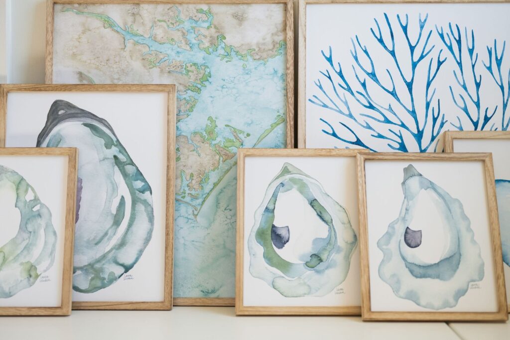 An array of coastal watercolor artwork showcasing maps, oysters, shells, and marine plant life in hues of blue