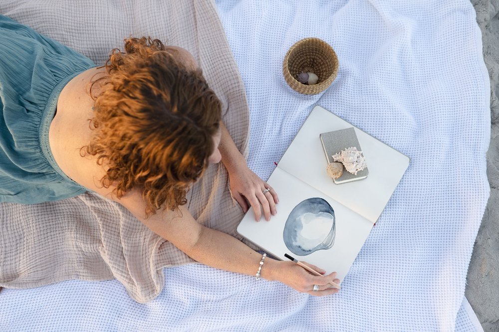 Meet Laura, a local watercolor artist painting on a beach blanket in Wilmington, North Carolina