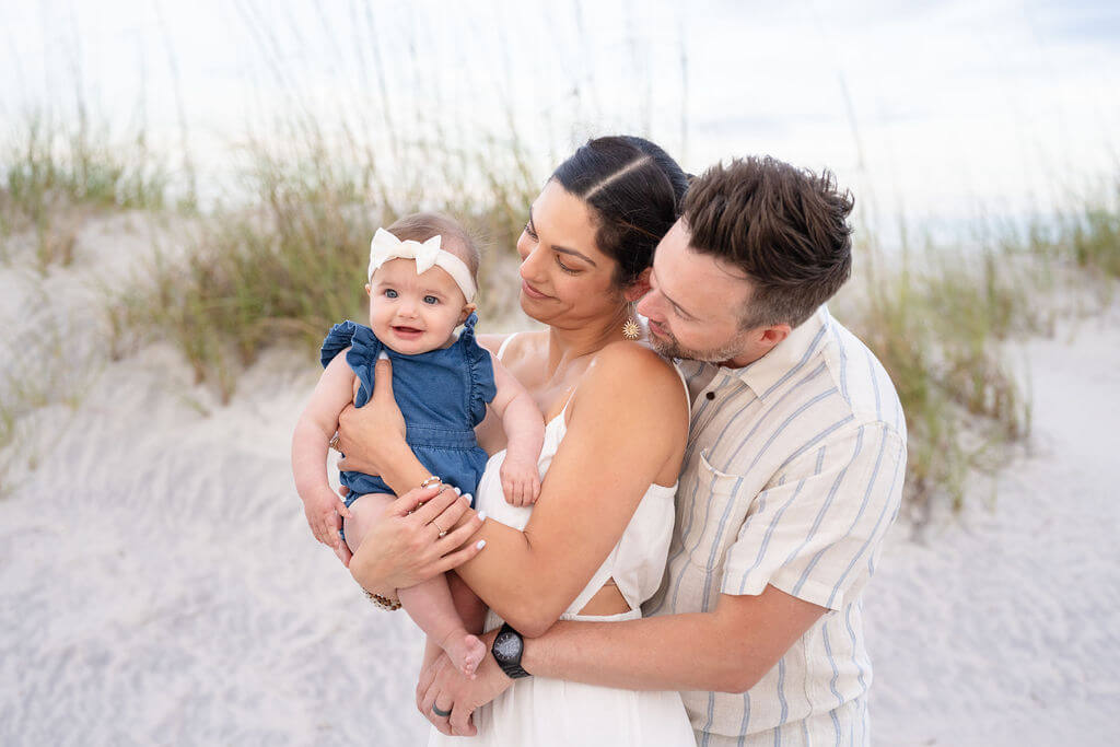 Family Photoshoot on the beach wearing blue stripes, denim blue, and white linen coordinated outfits for their family photography session.