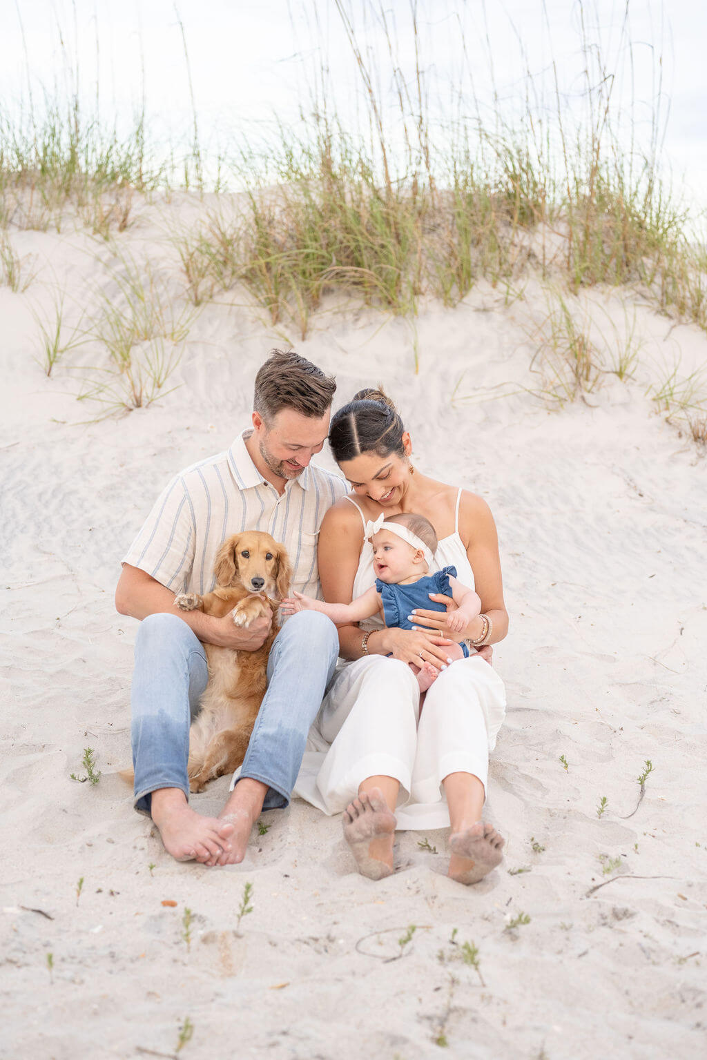 Family enjoying a little laugh for their family photography session with infant and family dog on North Topsail Beach in NC.