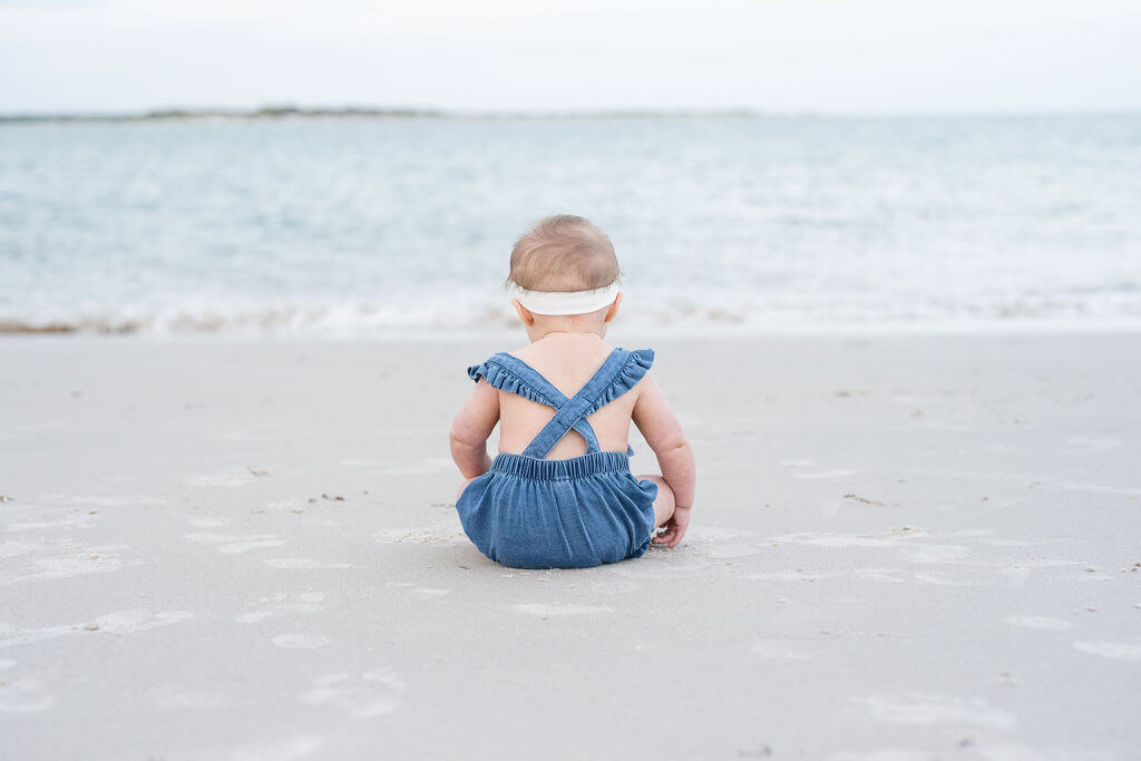 Baby girl soaking in the view of the beach in North Carolina; wearing her denim romper and white bow, she's the epitome of summertime at Topsail Beach. 