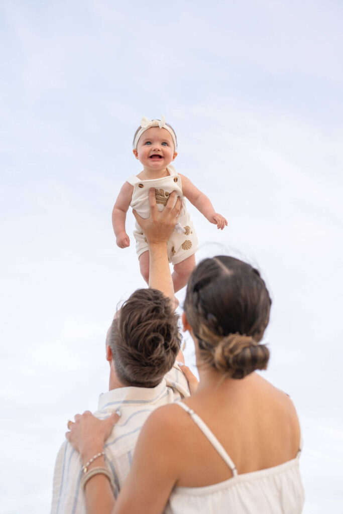 Happy baby girl enjoying play time with her parents on the beach in North Carolina. 