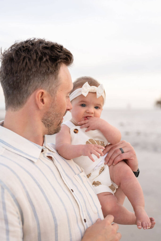 Perfectly coordinated outfits for family session on the beach in North Carolina. Baby girl with white bow on her head and neutral linens were the perfect combo for this daddy daughter duo.