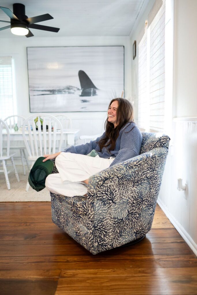 Meet Annie, a content queen with drive and spunk sitting in a coastal armchair with a smile on her face