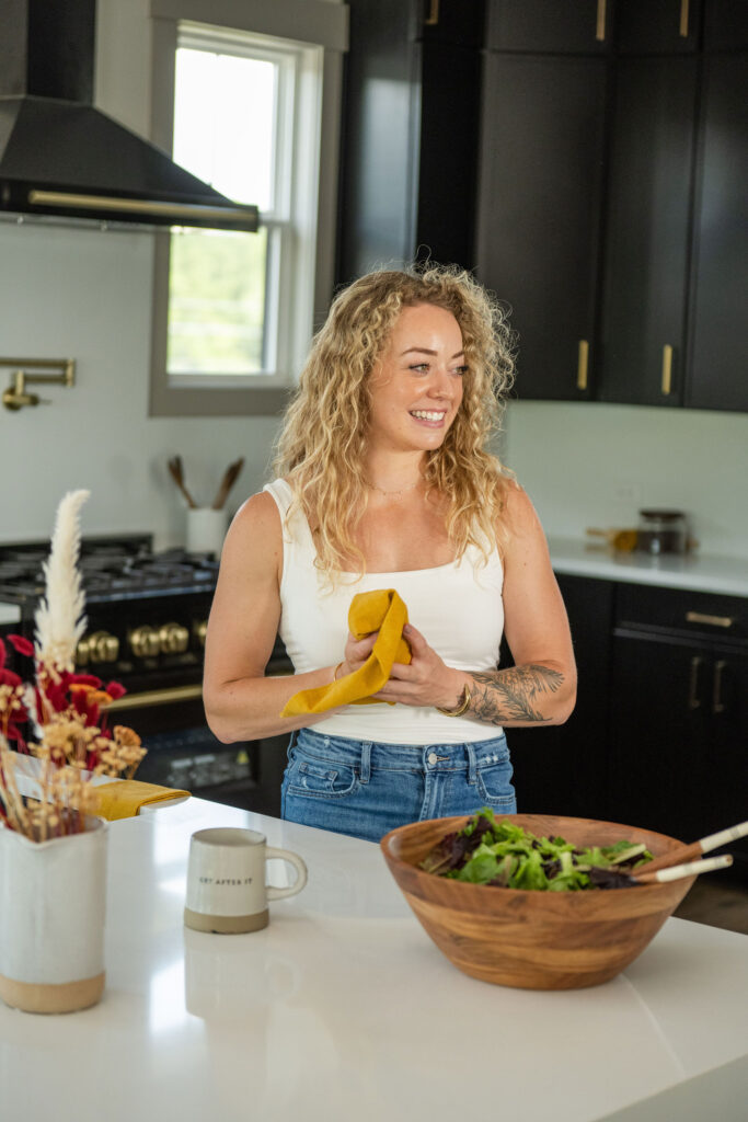 Colleen standing in the kitchen prepping a leafy green salad