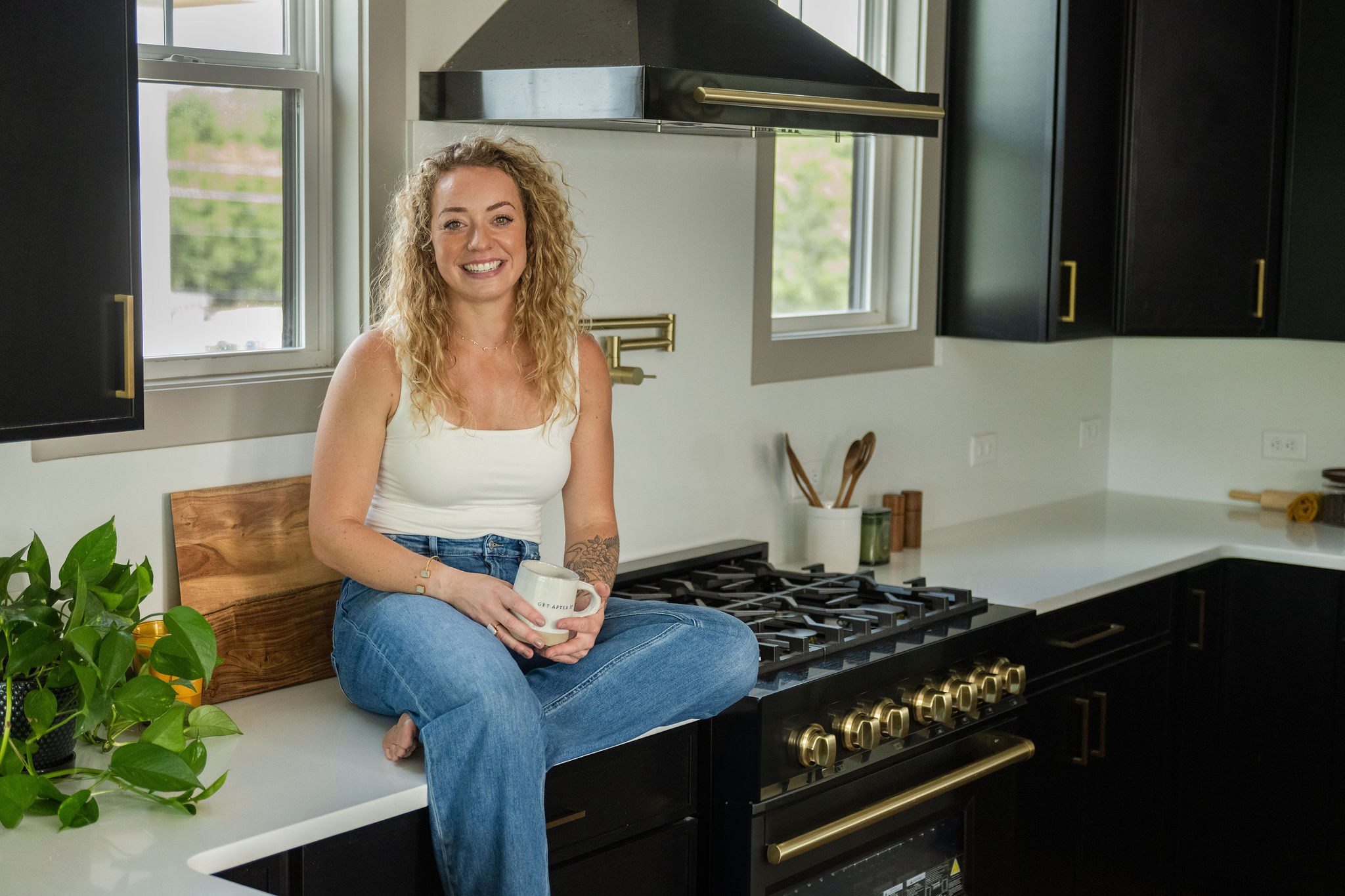 Colleen sitting on the kitchen counter holding a tan coffee mug