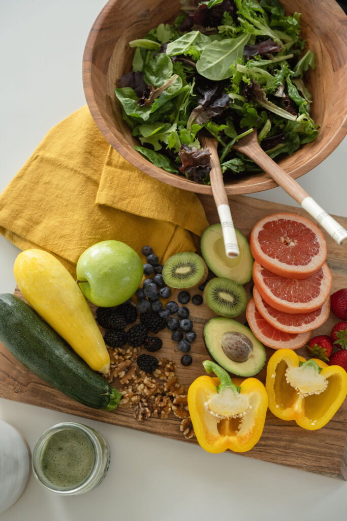 Closeup of a leafy green salad and cutting board full of fruit and veggies at a branding photography session