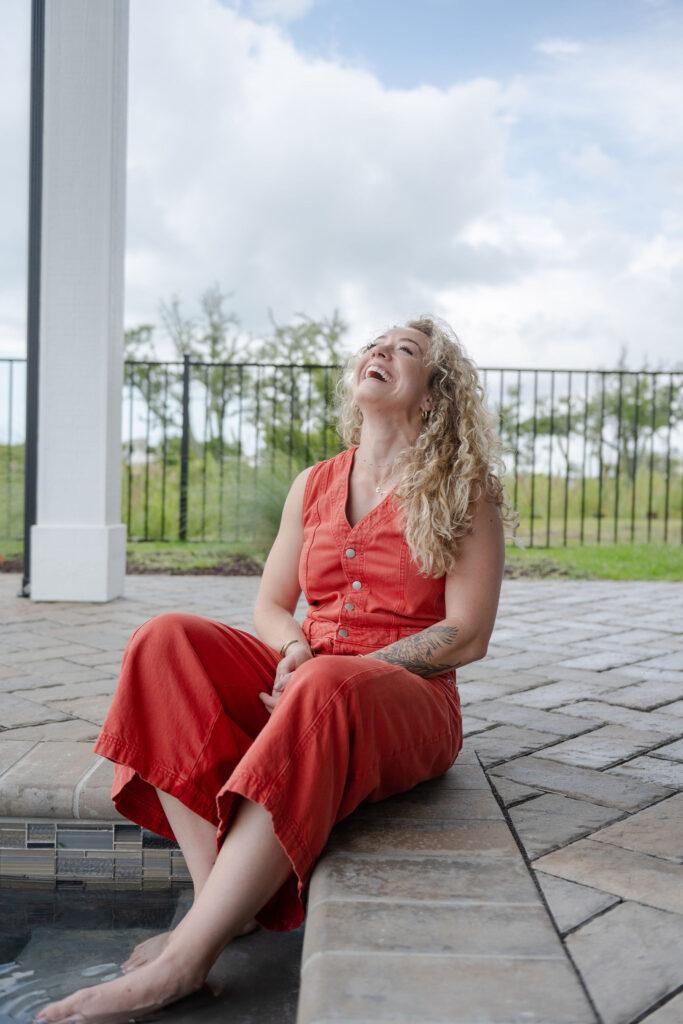 A branding photoshoot for a female fitness and health coach sitting with her toes in a pool.