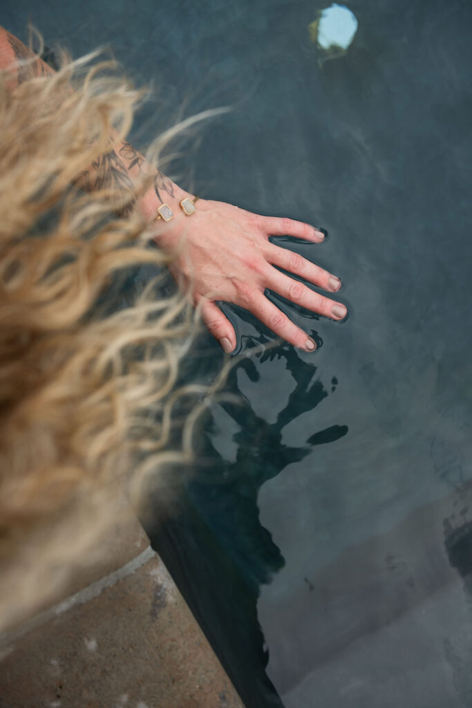 A branding photoshoot for a female fitness and health coach reaching into a pool.